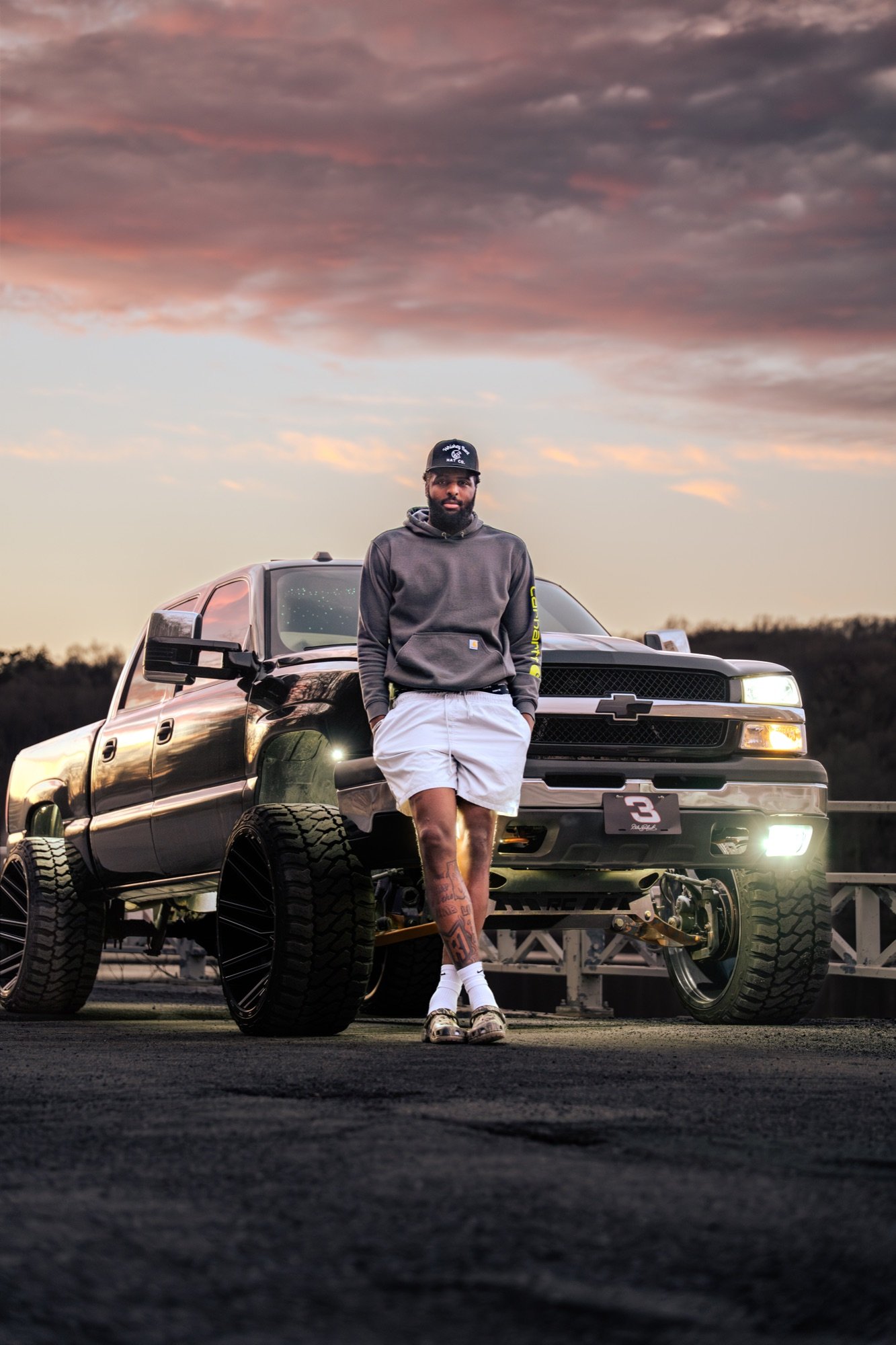 Lifted Cateye Chevy Silverado by a white fence at golden hour